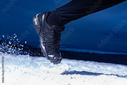 Athlete man is running during winter training outside in cold snow weather on the hills