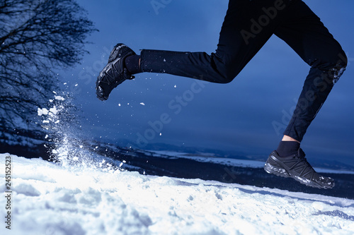 Athlete man is running during winter training outside in cold snow weather on the hills