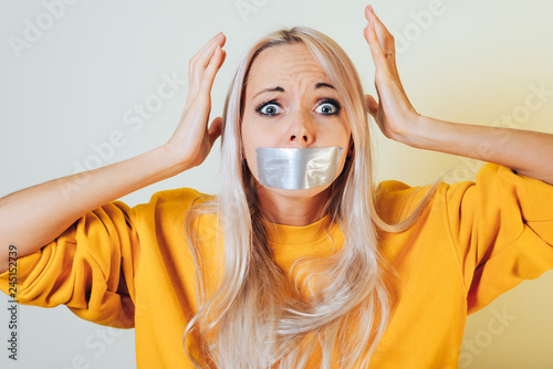 Portrait close-up of a girl with taped mouth holding hands on her head from what he saw terrible. The concept of what can not be said.