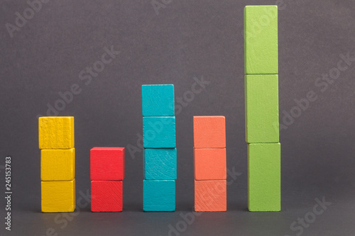 Toy wooden blocks as financial graph. Graph with four 4 steps. Infographic diagram, chart over grey or black or dark background. Multi-colored wooden blocks.