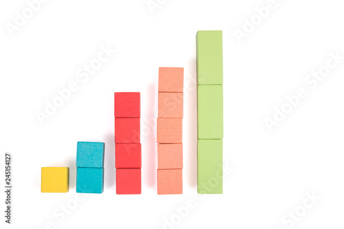 Toy wooden blocks as financial graph. Graph with four 4 steps. Growing chart. Infographic diagram  chart over grey or black or dark background. Multi-colored wooden blocks.
