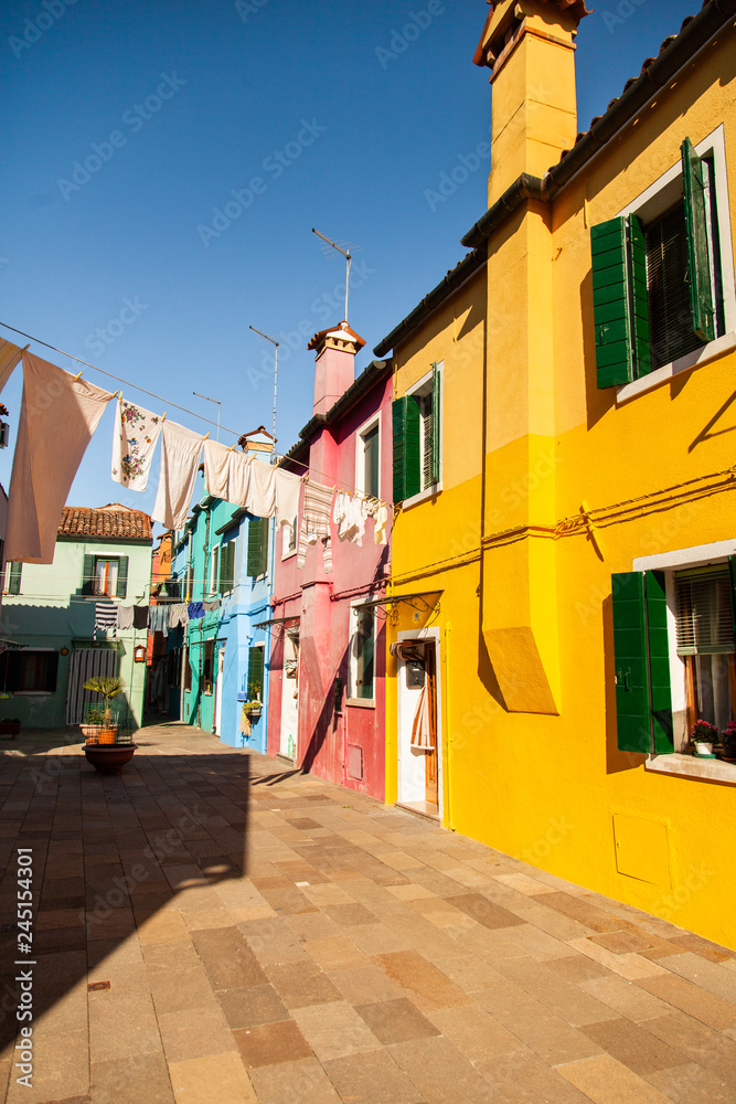 Burano island picturesque street with small colorful houses, smal water canal with beautiful reflections and  boats, Venice Italy 
