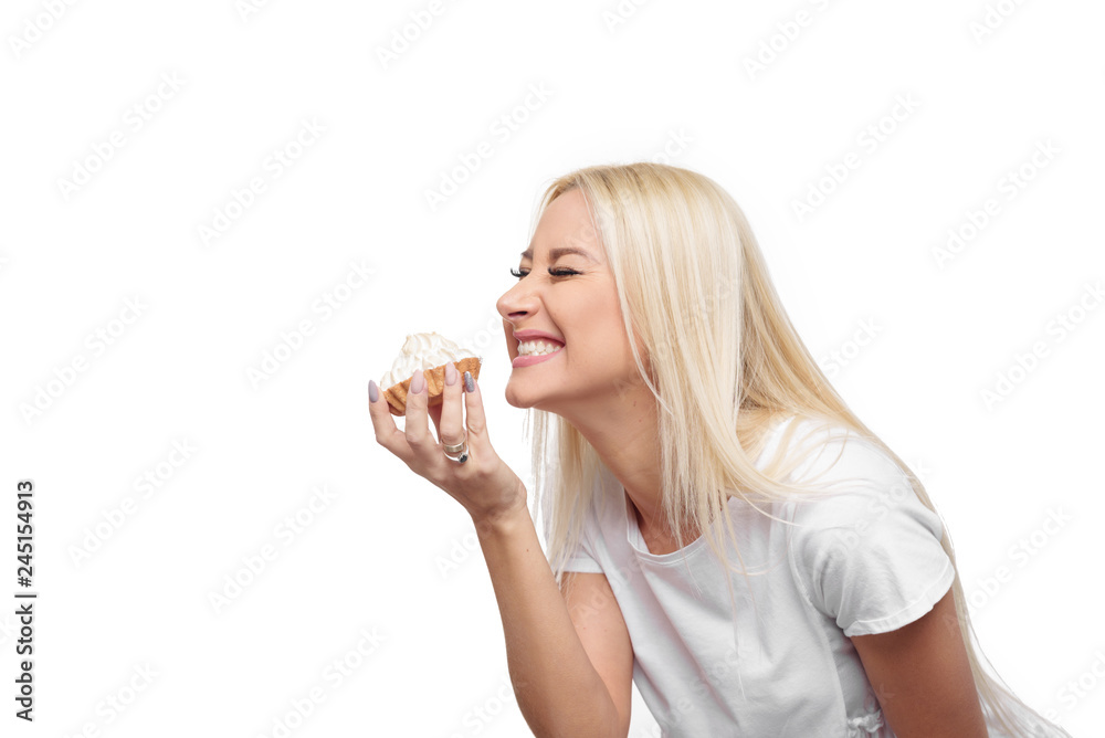 Diet. Dieting concept. Image of beautiful blond woman in white clothe isolated over white background holding and eating cake with pleasure Diet. Dieting concept. Image of beautiful blond woman in white clothe isolated over white background holding and eating cake with pleasure