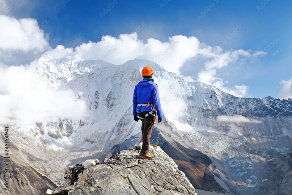 Climber reaches the summit of mountain peak. Success, freedom and happiness, achievement in mountains. Climbing sport concept.