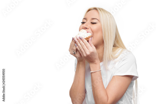 Diet. Dieting concept. Image of beautiful blond woman in white clothe isolated over white background holding and eating cake with pleasure 