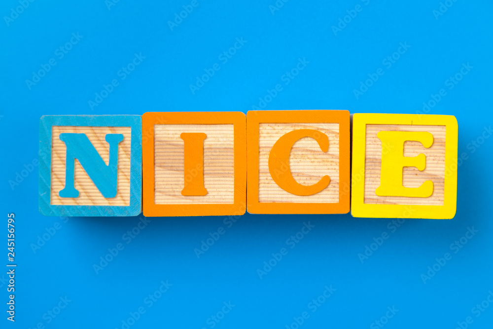 Nice. Wooden colorful alphabet blocks on blue background, flat lay, top view. Nice. Wooden colorful alphabet blocks on blue background, flat lay, top view.