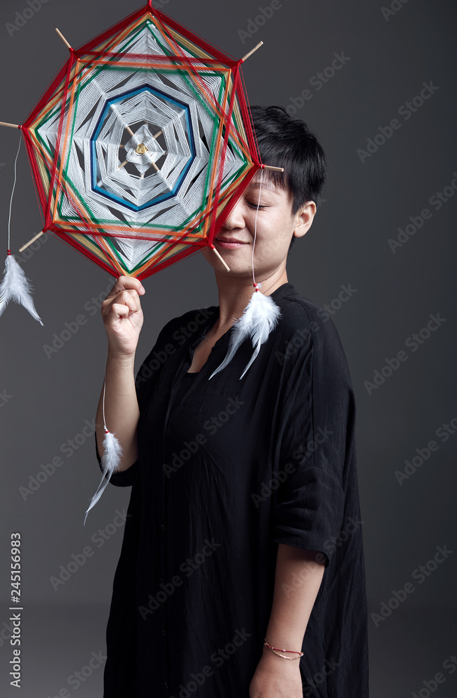 Fototapeta premium Beautiful Asian woman holding decorative braid indoors