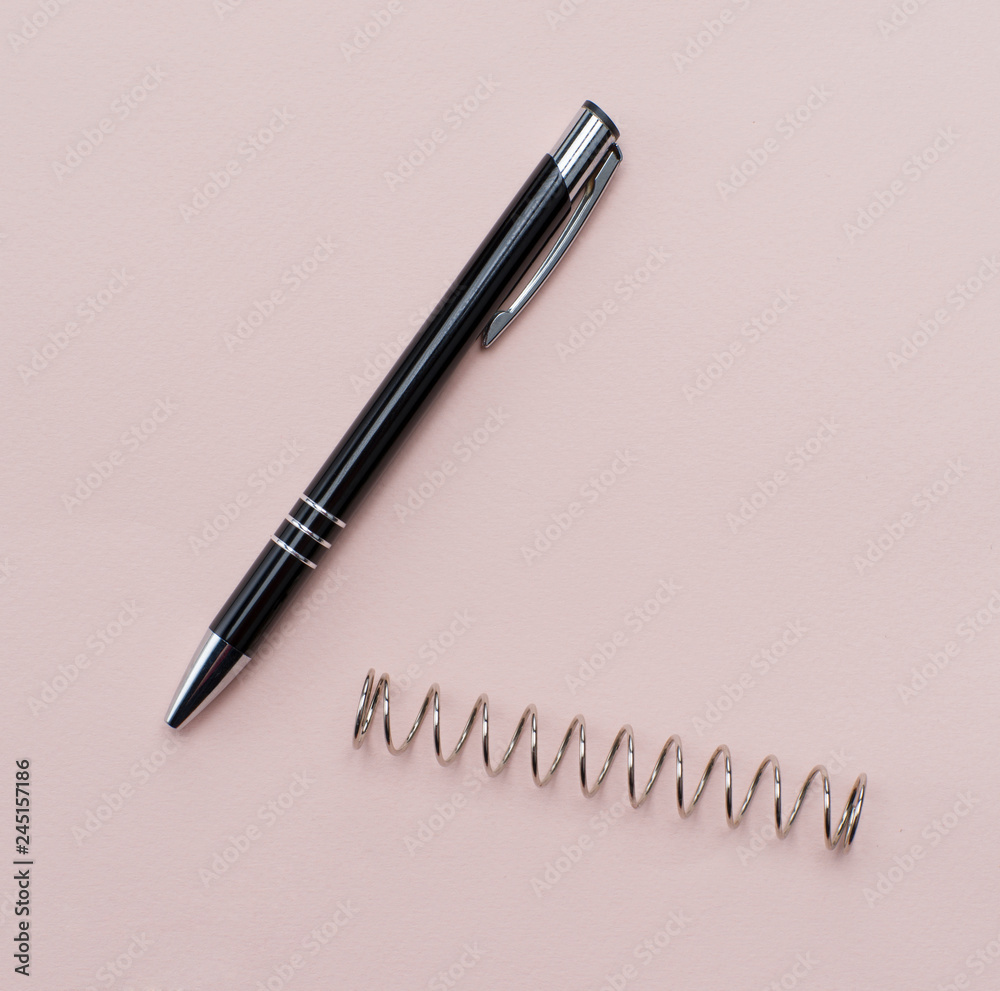 black ballpoint pen on a paper background. metal spring on the background black ballpoint pen on a paper background. metal spring on the background