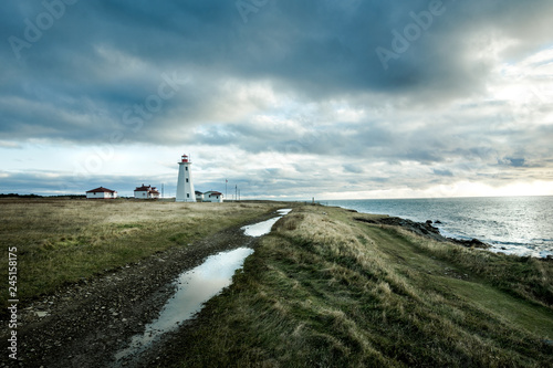 Newfoundland lighthouse perched on the ocean at sunset amid stormy clouds