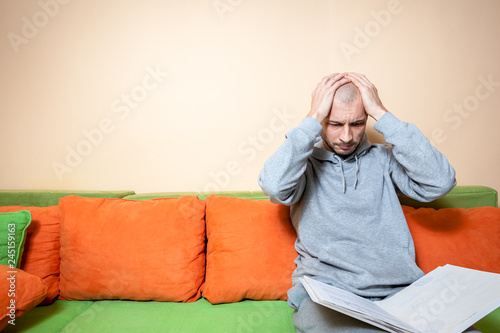 Young or middle age sick man in the casual clothes reading medical results on the papers from his doctor and realize that he have diagnosed a cancer or other sickness 