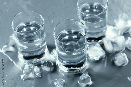 Cold vodka in shot glasses on a black background.