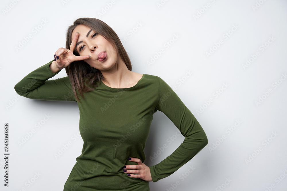 Woman pulling a hand gesture peace sign in front of her face Woman pulling a hand gesture peace sign in front of her face
