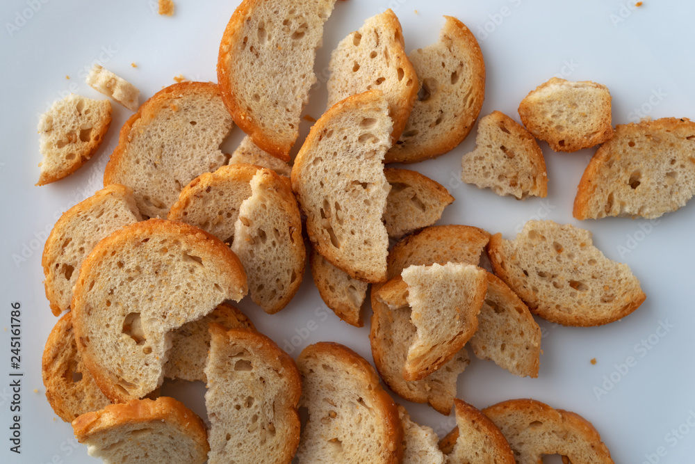 Top close view of broken pieces of sesame round melba toast on a white plate. Top close view of broken pieces of sesame round melba toast on a white plate.