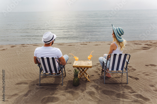 Couple on a deck chair relaxing on the beach. Happy couple enjoy on the beach during summer vacations