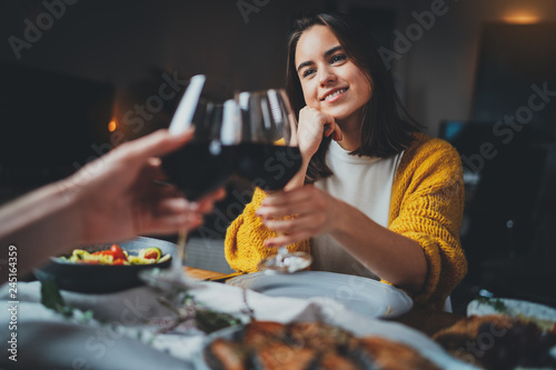 Romantic couple dating at night in restaurant, cozy atmosphere, beautiful young couple making cheers with glasses of red wine during romantic dinner, Sweet Couple Date Dinner