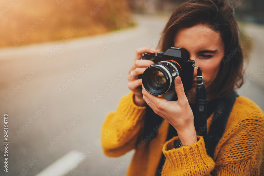 Young female photographer taking photograph on vintage camera outdoors, blank space for text message or design, tourist girl enjoying road trip in Europe, flare light - obrazy, fototapety, plakaty 