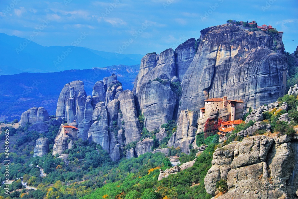 Monastery Meteora Greece. Stunning summer panoramic landscape. mountains and green forest against epic blue sky with clouds UNESCO heritage list object. Aerial view Great Meteor and Rousanou Monastery
