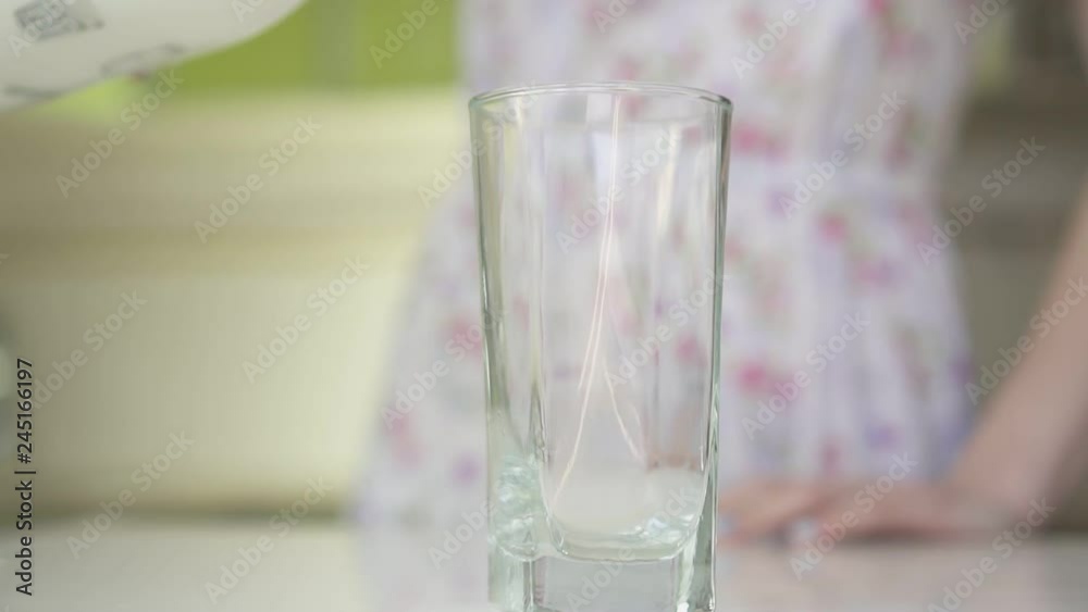 Woman in the kitchen pouring milk into a glass. Woman in the kitchen pouring milk into a glass.