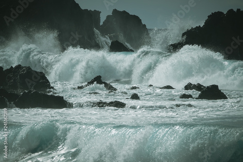 Waves crash along the black...