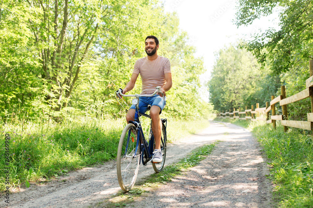 Naklejka premium people, leisure and lifestyle - happy man riding fixie bicycle at summer park