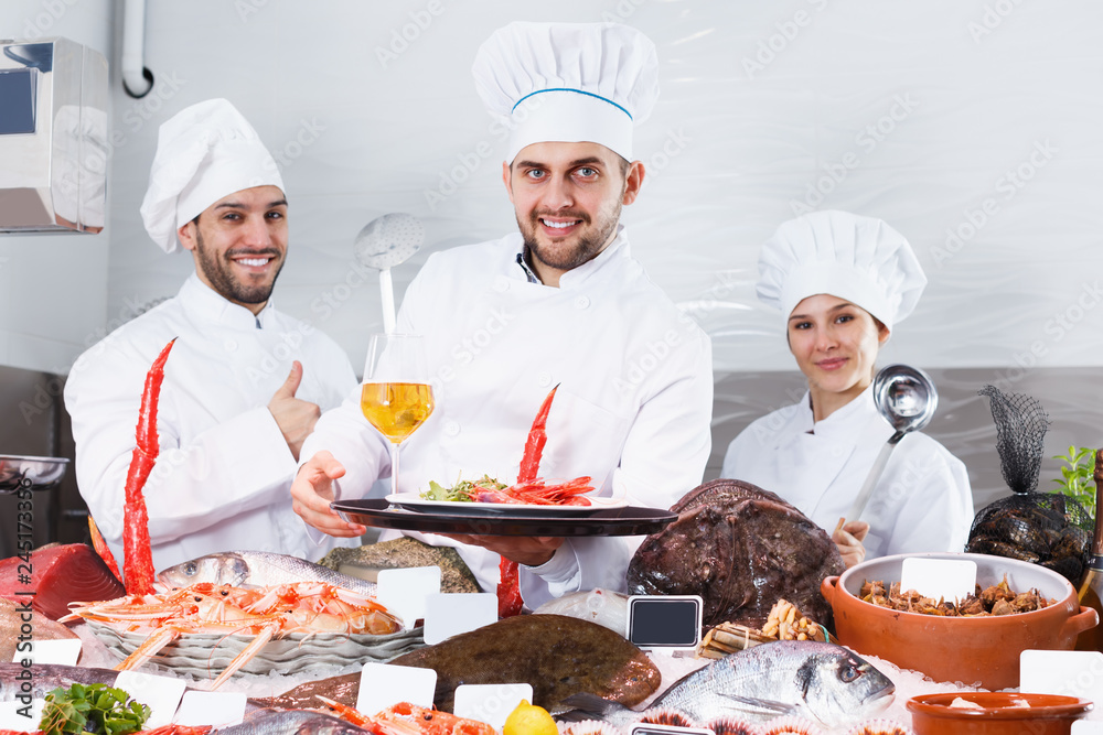 Smiling group of professional cooks of fish restaurant