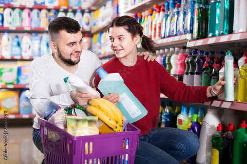 two friendly adult people in good spirits selecting detergents in the store