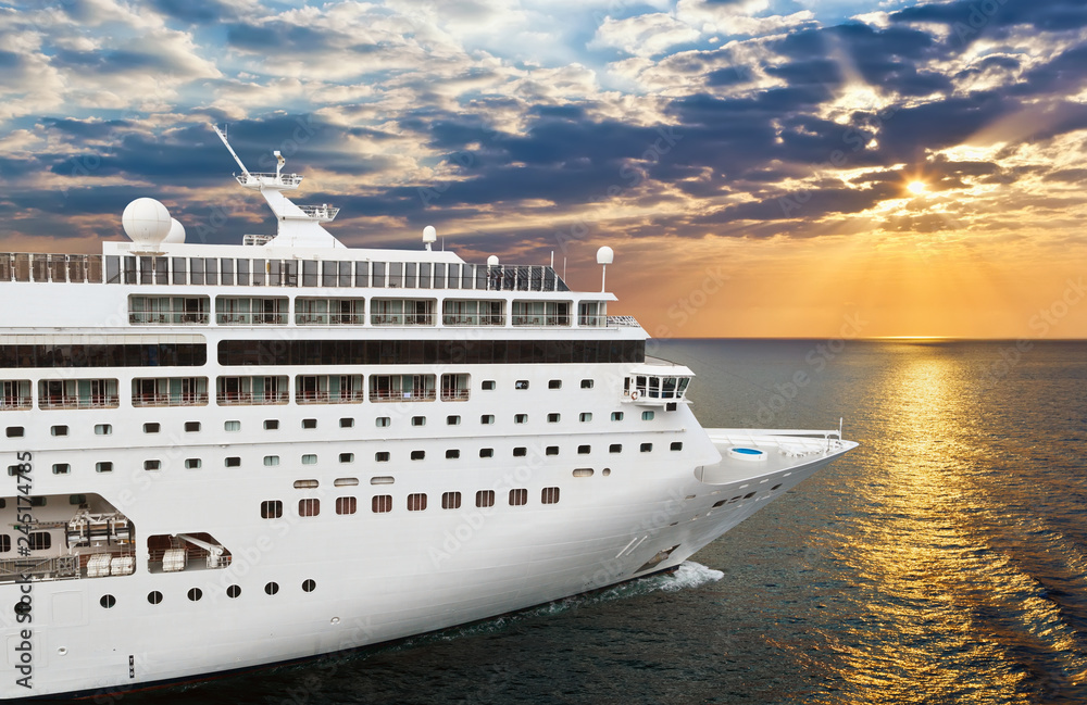 Luxury cruise ship sailing from port on sunset 