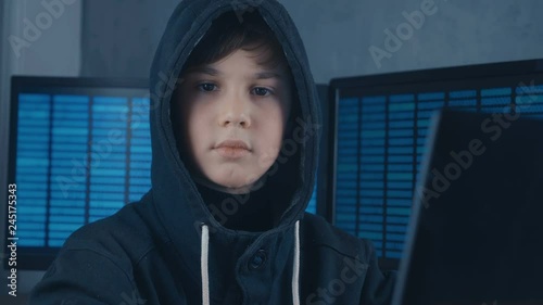 Portrait of a Young Prodigy Boy Hacker Programmer in the data center filled with display screens. Portrait of Child prodigy hacker.
