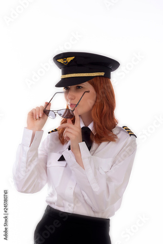 Young female pilot with red hair standing in airline uniform including a hat photo