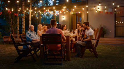 Sitting at the Dinner Table Handsome Young Man Plays the Guitar For a Friends. Family and Friends Listening to Music at the Summer Evening Garden Party Celebration. 