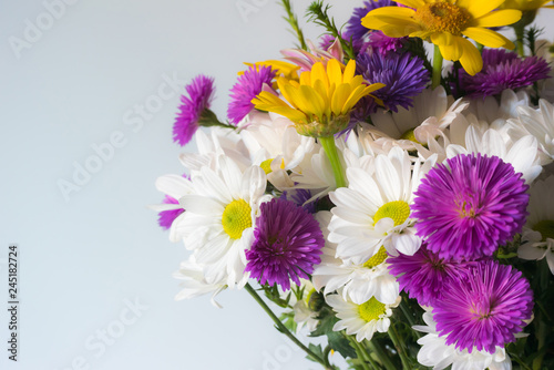 A fragment of a bouquet of beautiful bright flowers on a light background.