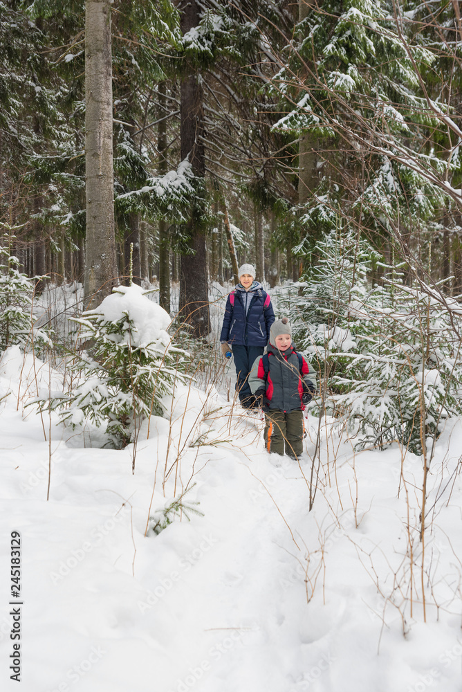 A woman with a child walking in the winter forest.