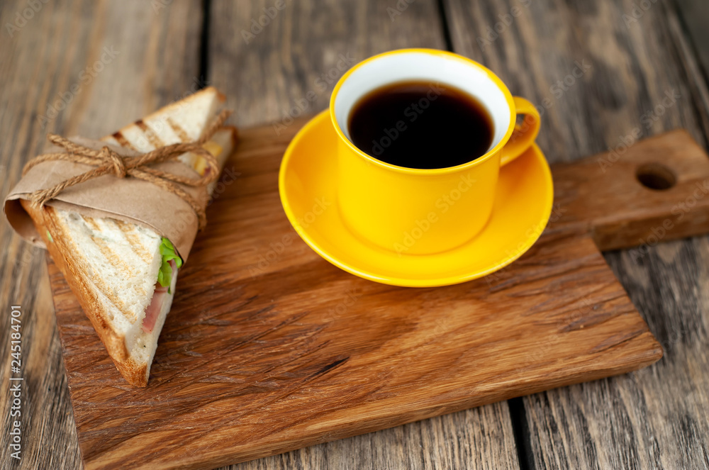 two delicious sandwiches with ham, cheese, lettuce and a cup of coffee on a wooden background two delicious sandwiches with ham, cheese, lettuce and a cup of coffee on a wooden background