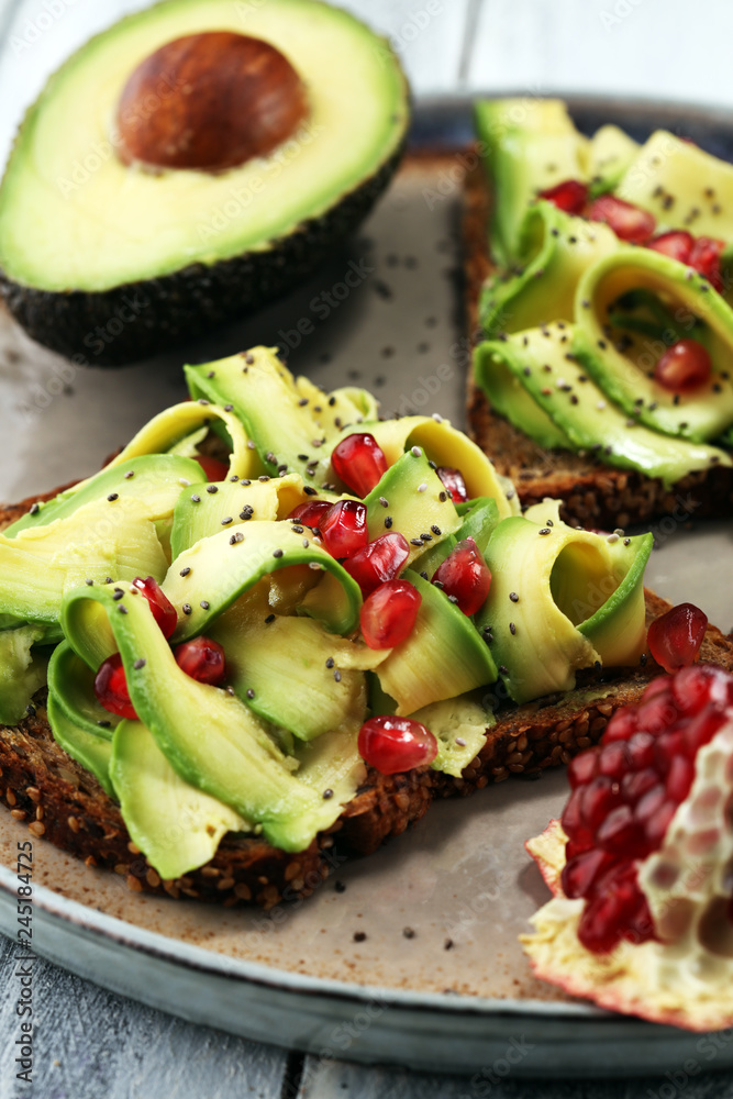 sliced avocado and ripe pomegranates on toast bread with spices and avocado. sliced avocado and ripe pomegranates on toast bread with spices and avocado.