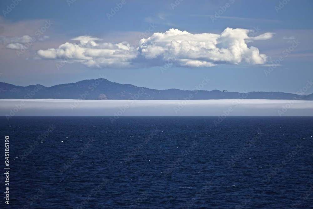 Fototapeta premium Morning at sea: Clouds and fog over Alaskan islands in the North Pacific Ocean.