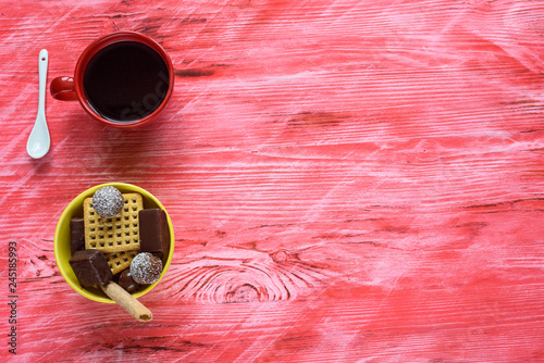 Yellow tareka with cookies and chocolates on a red wooden background, next to a coffee mug. photo