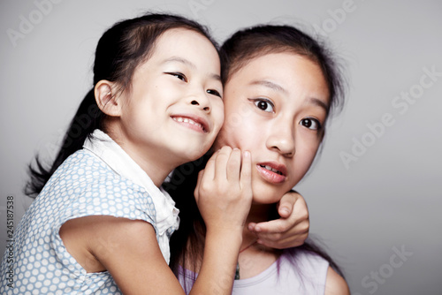 Two beautiful cute Asian little girls happily interacting indoors