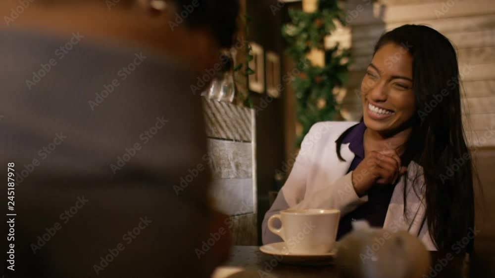 Two women in a coffee shop chatting and laughing