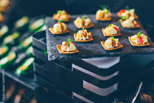 Strawberry, pineapple, cheese snacks with almonds on black slate in a buffet. Event catering concept. photo