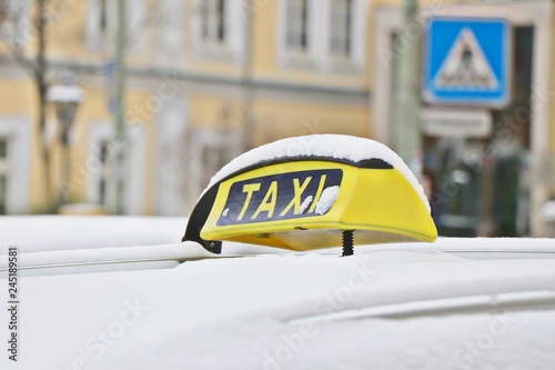 Yellow taxi sign on car overed with snow in Germany.