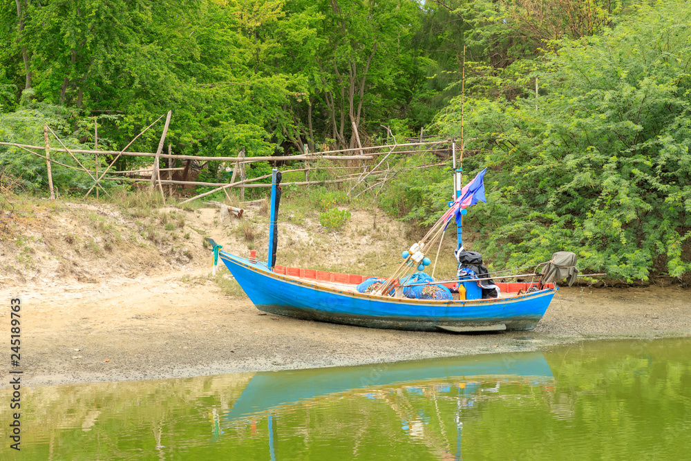 Traditional fishing boat on river bank near fisherman village Traditional fishing boat on river bank near fisherman village