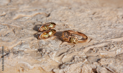 Gold ring and earrings lie on the stone surface photo