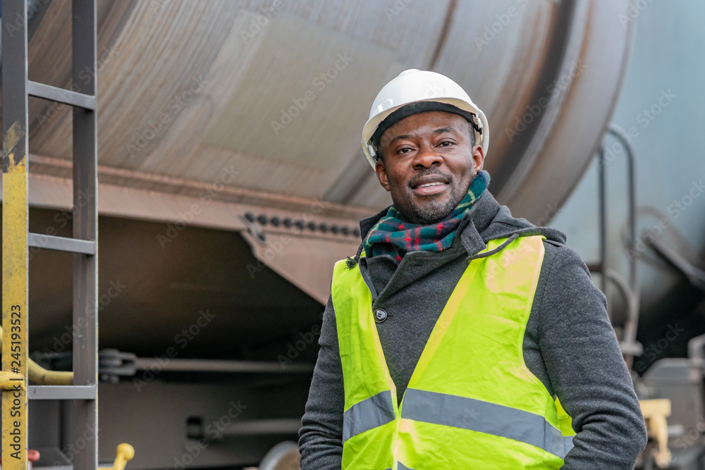 Portrait of a smiling and satisfied African American engineer wearing protective workwear posing on construction site Portrait of a smiling and satisfied African American engineer wearing protective workwear posing on construction site