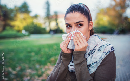 Cold and flu. Woman blowing her nose with a tissue