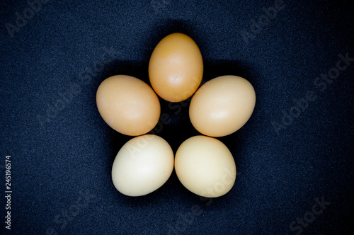 Five brown eggs on black background