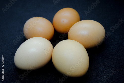 Five brown eggs on black background