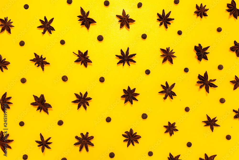 Star anise and allspice in lines with hard shadow on yellow background, flat lay image. Star anise and allspice in lines with hard shadow on yellow background, flat lay image.