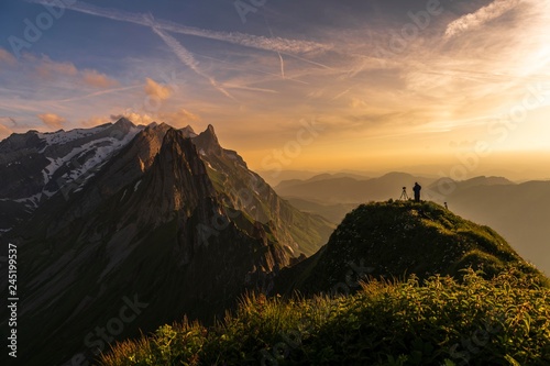 Photographer on grassy ridge at sunset with Santis peak in the background, Wasserauen, Appenzell, Switzerland, Europe photo