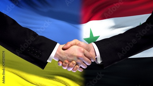 Ukraine and Syria handshake, international friendship relations, flag background