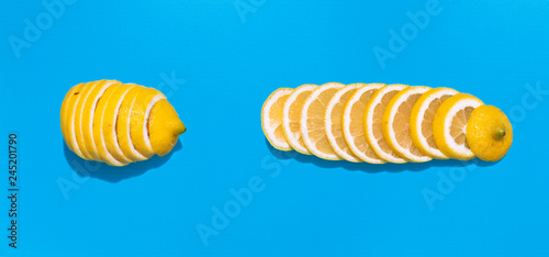 Whole yellow sliced lemon on blue background  flat lay image.